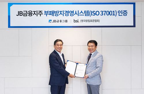 JB금융그룹 김기홍 회장(왼쪽)이 BSI 코리아 송경수 총괄 책임으로부터 지난 30일 서울 여의도 JB빌딩에서 'ISO 37001' 인증서를 수여받는 모습.JPG