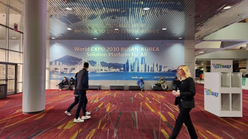 '2030 부산엑스포 유치 기원' 대형 현수막이 게시된 CES 2023 행사장인 美 라스베이거스 컨벤션 센터안에서 관람객들이 지나가고 있다.