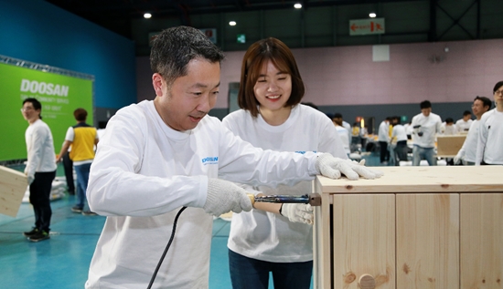 ▲ 박정원 두산그룹 회장이 19일 '두산인 봉사의 날(Doosan Day of Community Service)'을 맞아 서울무역전시컨벤션센터에서 임직원들과 함께 지역사회 가정에 전달할 가구를 만들고 있다.