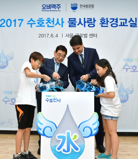 ▲ 오비맥주와 사단법인 한국물포럼은 4일 서울 종로구 서울글로벌센터에서 서울·경기·대전 지역 초등학생 60여 명을 초청해 '수호천사 물 사랑 환경교실'을 열었다. (사진 왼쪽부터) 이태윤 어린이, 한국물포럼 이정무 총재, 오비맥주 김도훈 대표, 허예나 어린이가 수호천사 캠페인의 로고를 형상화한 기념물에 함께 마중물을 붓는 '합수식'을 진행하고 있다.