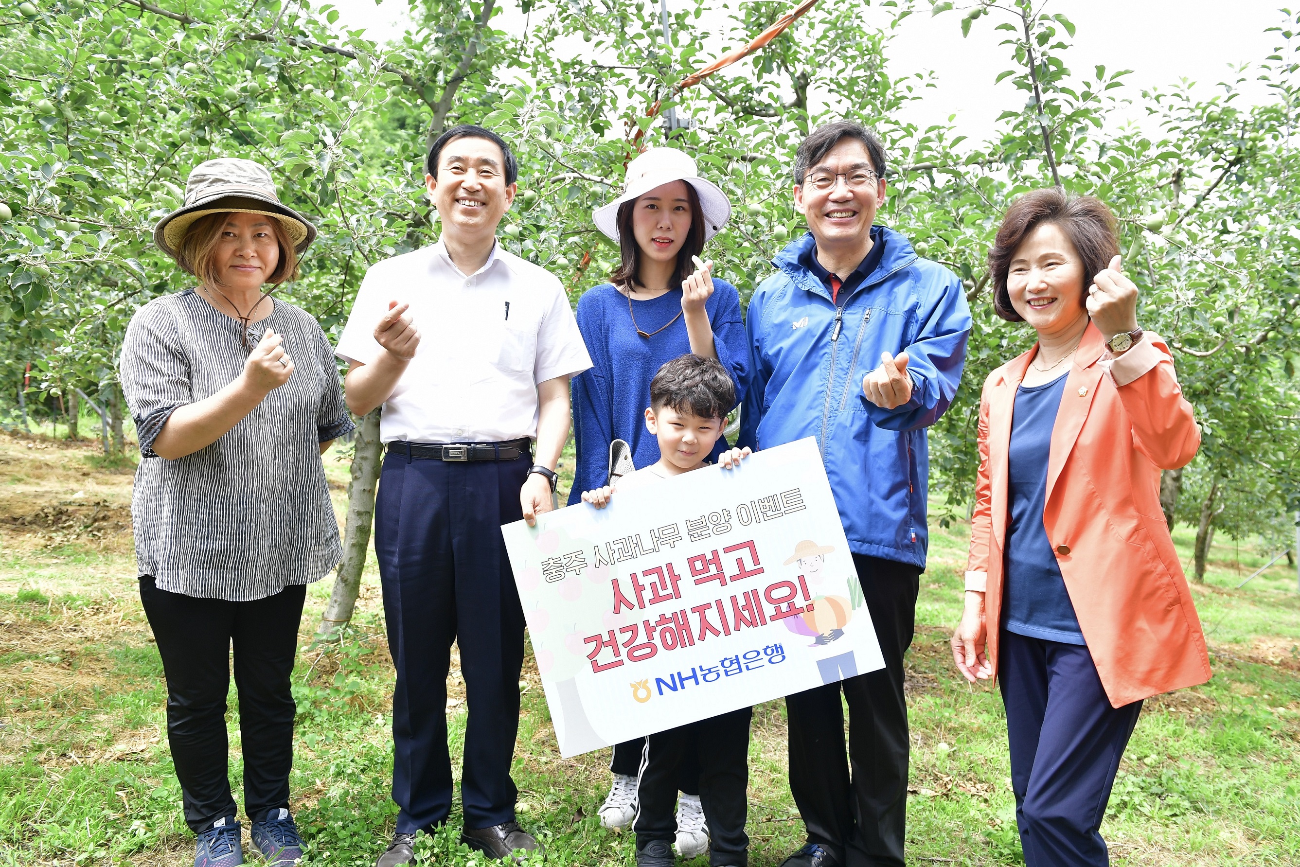 ▲ 이대훈 은행장(사진 오른쪽 두번째), 조길형 충주시장(사진 왼쪽 두 번째), 허영옥 충주시의장(사진 오른쪽 첫 번째)이 고객과 함께 사과나무 앞에서 기념촬영을 하고 있다