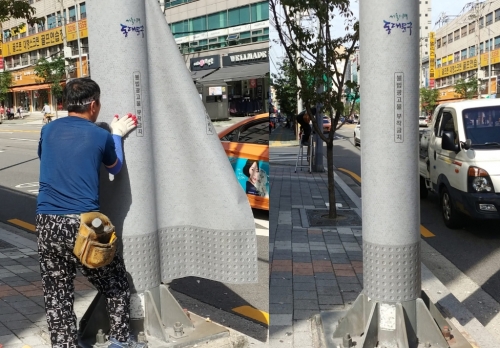 '불법 광고물 부착방지시트'를 가로등 기둥에 붙이고 있다.