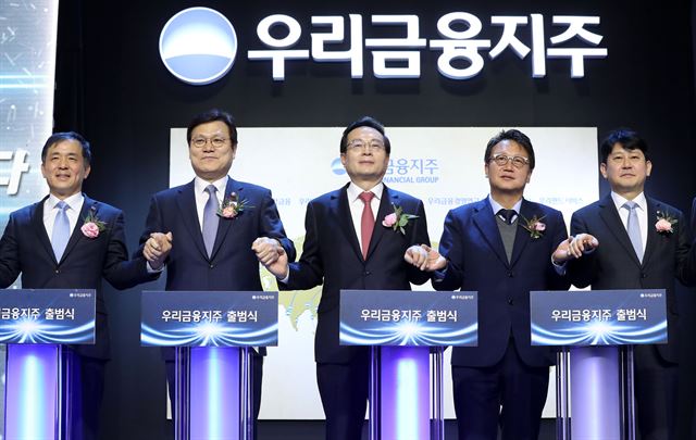 ▲ 손태승(가운데) 우리금융지주 회장 겸 우리은행장이 14일 서울 중구 우리은행 본점에서 열린 우리금융지주 출범식에서 현판 점등식을 마친 뒤 기념촬영 하고 있다. 왼쪽부터 위성백 예금보험공사 사장, 최종구 금융위원장, 손 회장, 민병두 국회 정무위원장, 유광열 금융감독원 수석부원장.