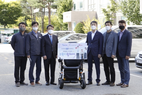 ㈜만도 홍영일 상무(왼쪽에서 3번째), 한국교통안전공단 강원본부장 이장규(오른쪽에서 3번째), 희망VORA 김영준 사무국장(오른쪽에서 2번째)이 오뚝이 휠체어 선정 가정을 방문하여 휠체어를 전달하고 있다.