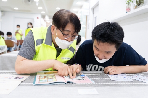 사진은 하영규 LG전자노동조합 위원장(왼쪽)이 장애청소년에게 가전 사용법을 교육하는 모습.