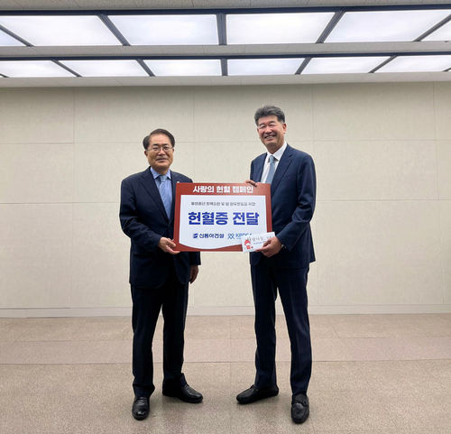 진현기 신동아건설 대표이사(오른쪽)가 장태평 한국혈액암협회 협회장(왼쪽)에게 헌혈증을 전달하고 기념촬영을 하고 있다.