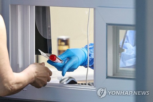 7일 서울 용산구보건소에 마련된 선별진료소를 찾은 시민이 검체통을 받고 있다.