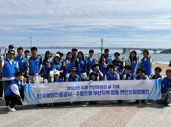 한국해양진흥공사와 수협은행 임직원들이 광안리 해수욕장 연안정화활동을 기념해 단체촬영을 하고 있다.