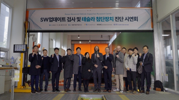 11월 28일(화) 세종자동차검사소에서 개최된 'SW업데이트 검사 및 테슬라 첨단장치 진단 시연회' 참석자들이 기념사진을 찍고 있는 모습-국토교통부 자동차운영보험과 임월시 과장(좌측에서 여섯 번째), 한국교통안전공단 자동차검사본부오태석 본부장(좌측에서 다섯 번째), 테슬라 임원 Brian Boggs(좌측에서 일곱 번째)