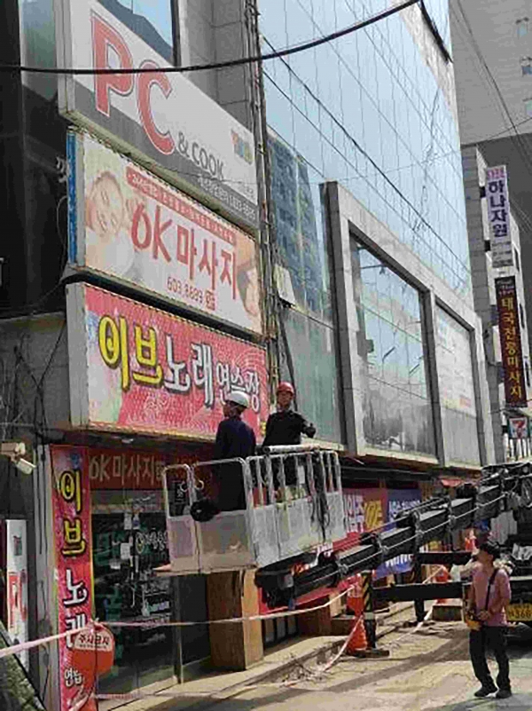 성남시 관계자들이 중원구 한 건물의 주인없는 간판을 정비하고 있다.