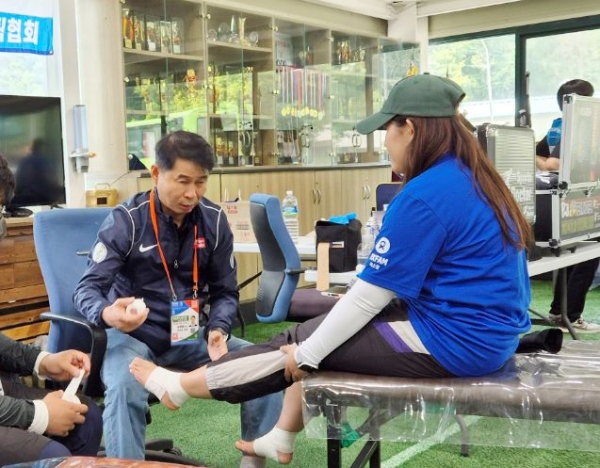 김태영 박사(대회의무위원장)가 외국인 여성참가자의 발목에 스포츠테이핑을 해주고 있는 모습.
