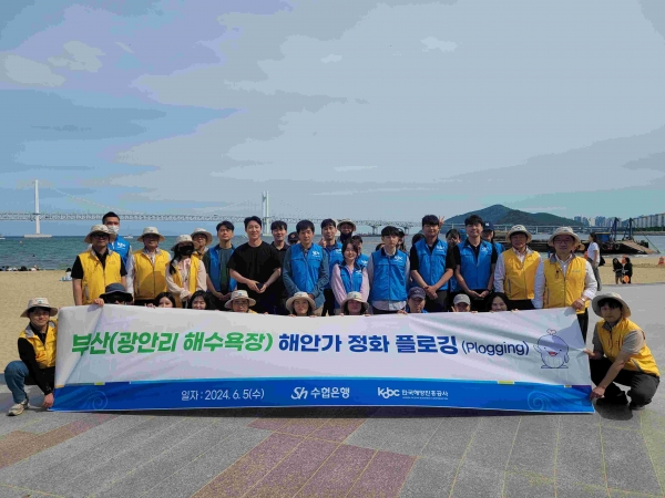 한국해양진흥공사와 수협은행 임직원들이 광안리 해수욕장 연안정화활동을 기념하여 단체사진을 찍고 있다.