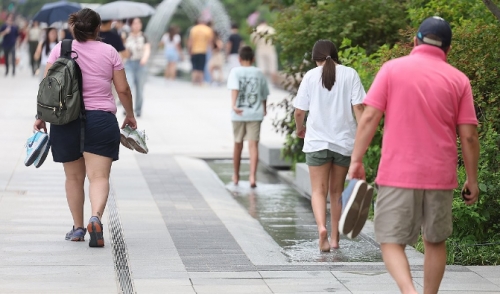 무더위가 계속된 21일 오후 서울 광화문 광장에서 일부 시민이 신발을 벗고 물 위로 더위를 식히며 걷고 있다. 사진=연합뉴스