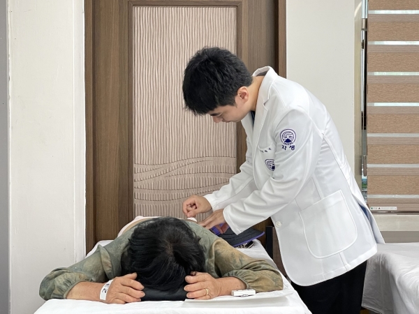 자생한방병원 의료진이 진료소를 방문한 어르신에게 침치료를 진행하고 있다.
