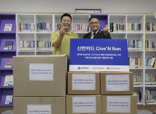 구세군지역아동복지센터 내 아름인도서관에서 이두형(왼쪽) 신한카드 사내 러닝 동호회 회장과 박준경 구세군지역아동복지센터장이 기념 사진을 촬영하고 있다. [사진=신한카드]