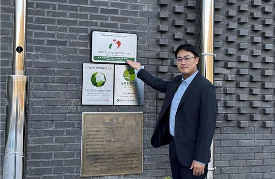 한국교통안전공단 김천드론자격센터 전홍수 선임연구원이 BF 인증 현판을 가리키며 기념 사진을 찍고 있는 모습.