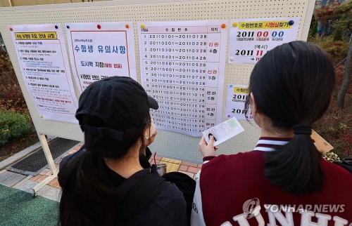 대학수학능력시험을 하루 앞둔 13일 오전 서울 성동구 성수고등학교에서 수험생들이 수험표를 들고 고사장을 확인하고 있다.