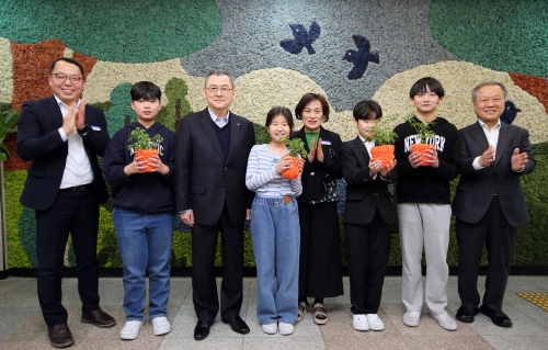 ▲ 한화 김신연 사장(왼쪽 세번째)이 진잠초 학생들과 함께 공기정화를 위해 한화가 벽면에 조성한 모스월 앞에서 반려 식물을 들고 기념촬영을 하고있다. [사진= 한화그룹 제공]