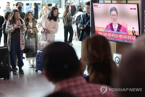 4일 서울역 대합실에서 이용객들이 윤석열 전 대통령 탄핵심판 선고 생중계를 보고 있다.