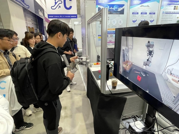 한국공학대학교 Grand-ICT센터 부스에서 협동로봇 시연을 관람 중인 참관객들. 모니터를 통해 로봇 작동 과정이 실시간으로 전시되고 있다.