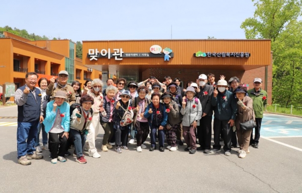8일 강원도 춘천시 신북읍 국립춘천숲체원에서 시내버스를 타고 숲을 체험하는 시니어웰라이프 교육 참여 어르신들에게 춘천숲체원 직원들이 카네이션을 달아드리고 기념 촬영을 하고 있다. (사진제공=한국산림복지진흥원 국립춘천숲체원)