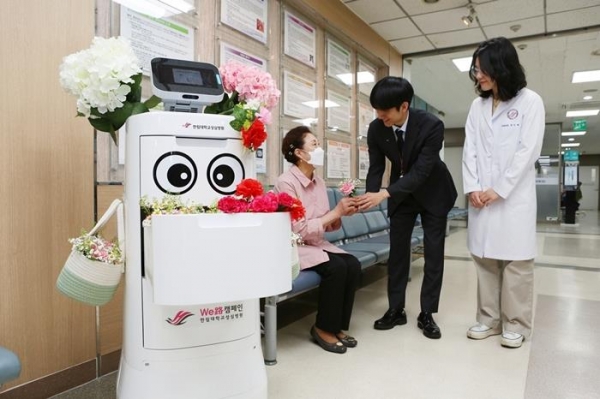 8일 어버이날을 맞아 한림대성심병원 직원들이 물품을 나르는 배송로봇 '나르미'룰 활용해 어르신 방문객에게 카네이션을 전하고 있다.