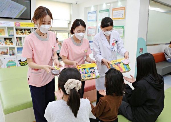 한림대성심병원 직원들이 5월 가정의 달을 맞아 소아청소년과 외래 대기공간에서 어린이 환자들에게 선물을 전달하고 있다.