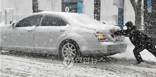 서울지방에 기록적인 폭설이 내린 4일 오전 서울 종로에서 한 시민이 빙판에 미끄려진 차량을 뒤에서 힘겹게 밀고 있다